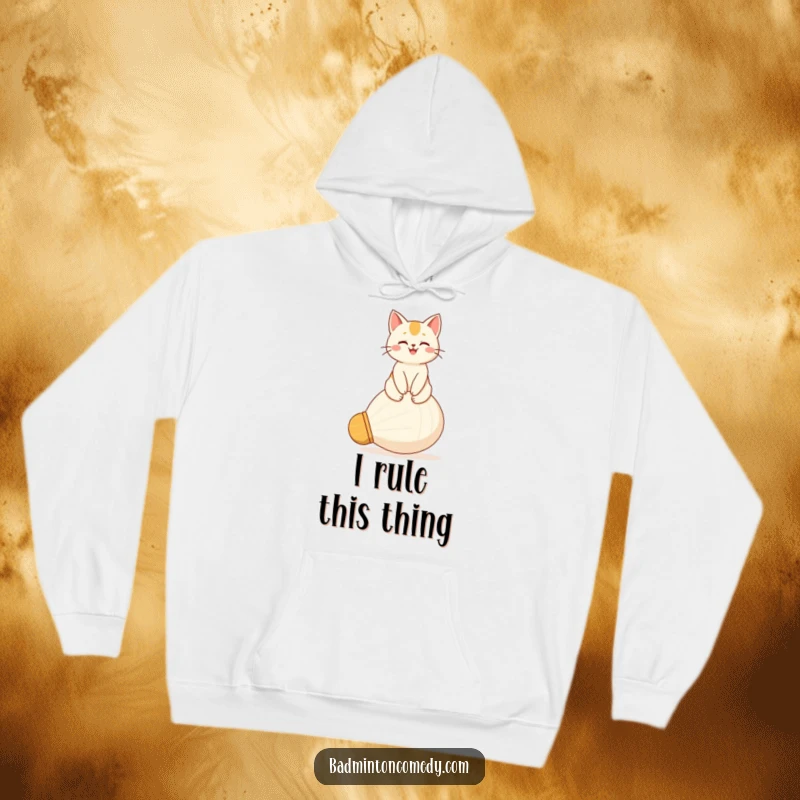 Funny hoodie featuring a happy cat sitting majestically on a large shuttlecock, exuding pride and contentment.